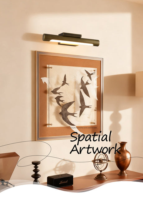 Bronze bar lit over a framed bird artwork in a warm evening room