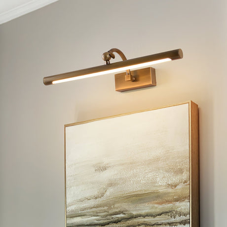 Bronze bar lit above a framed canvas, the pivot arm seen against a pale wall