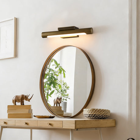 Bronze bar above a round mirror over a console with books and a plant