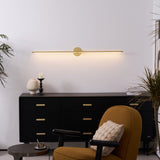 Slim rod lit above a black sideboard with candlesticks and a mustard armchair
