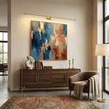 Slim rod lit above a framed canvas over a walnut sideboard and a pale armchair