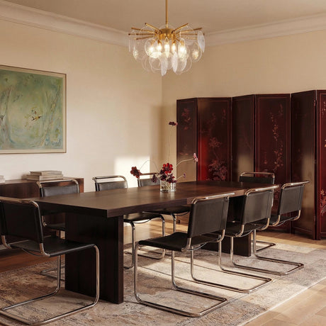 The fitting above a long dining table with chairs, a painted artwork and a screen