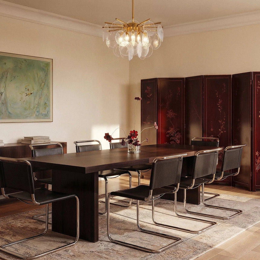 The fitting above a long dining table with chairs, a painted artwork and a screen