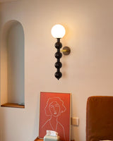 Sconce lit beside an arched niche above an armchair and a bold print