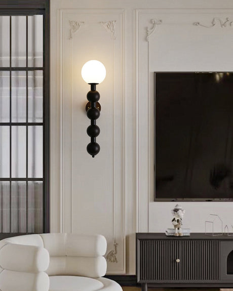 Sconce lit above a fluted console beside two pale armchairs