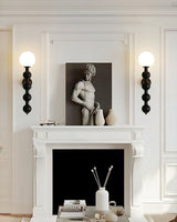 Two sconces lit either side of a white fireplace with a framed sculpture