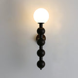 The globe lit warm at the top of the stacked beads on a pale wall