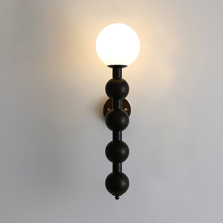 The globe lit warm at the top of the stacked beads on a pale wall