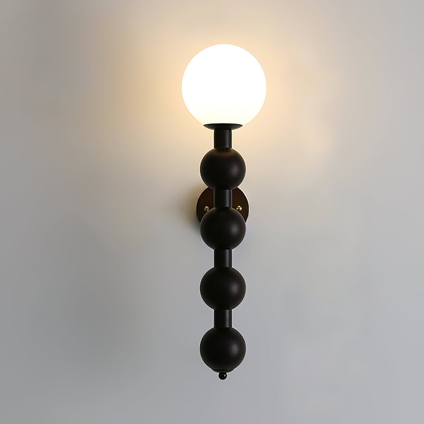 The globe lit warm at the top of the stacked beads on a pale wall