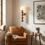 Sconce lit beside a leather armchair with a framed print and a side table