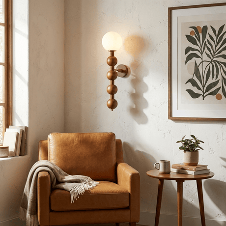 Sconce lit beside a leather armchair with a framed print and a side table