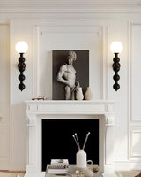 Two sconces lit either side of a mantel holding a small stone sculpture