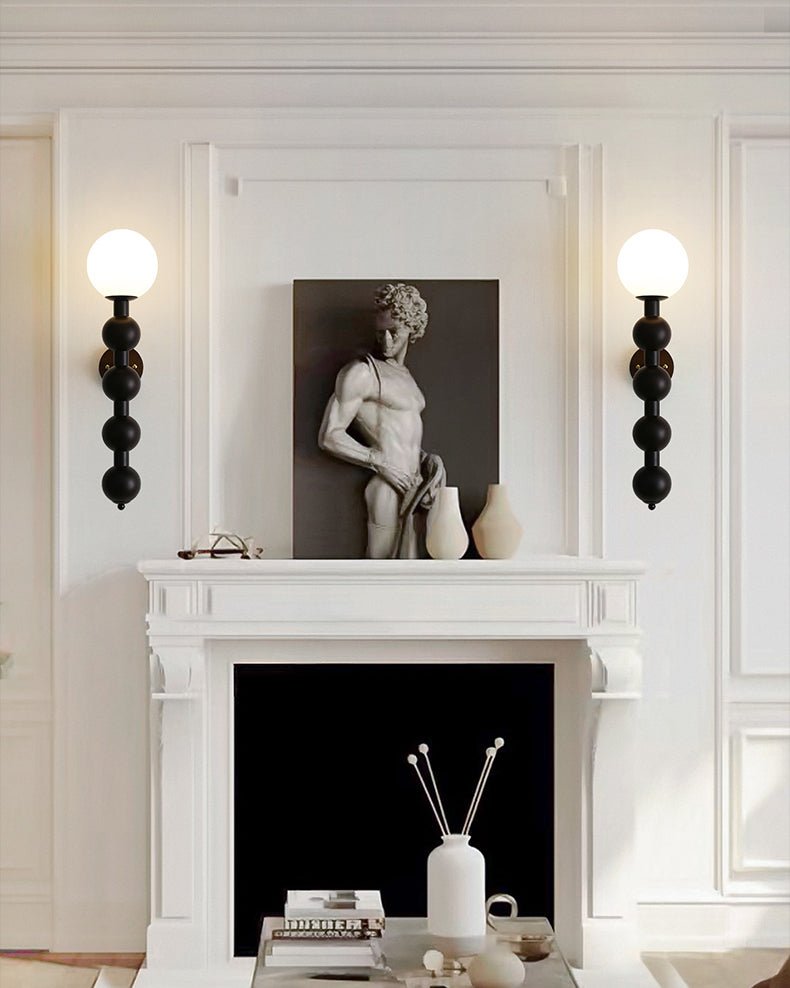 Two sconces lit either side of a mantel holding a small stone sculpture