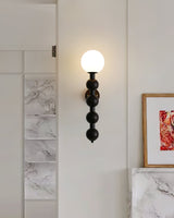 Sconce lit beside framed prints above a marble topped console