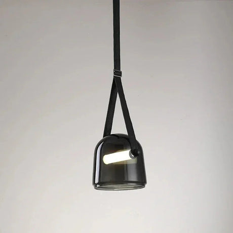 The black plated glass shade on its leather strap on a plain background