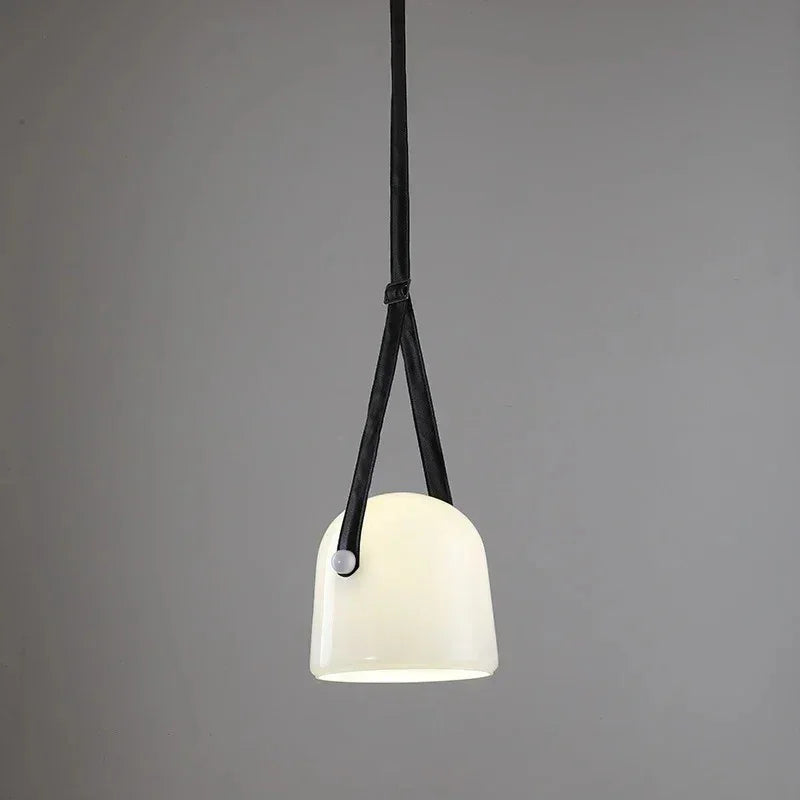 The milk white glass shade on its leather strap on a plain background