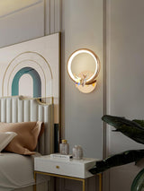 The butterfly ring beside a white headboard above a nightstand and a plant