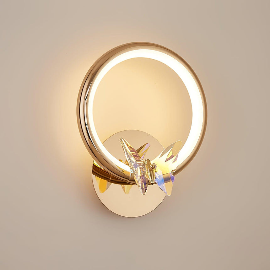 The ring lit warm on a beige wall, the butterfly catching the light