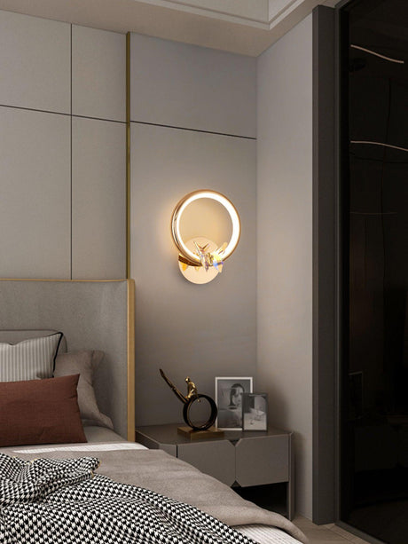 The butterfly ring lit above a nightstand beside a bed with a checked throw