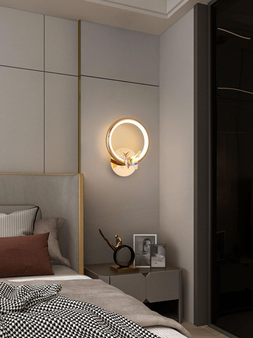 The butterfly ring lit above a nightstand beside a bed with a checked throw