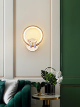 The butterfly ring on a paneled wall above a green velvet sofa and a side table
