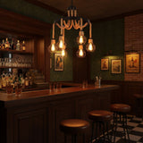 Chandelier lit above a dark bar counter with stools and bottles