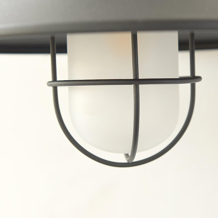 Close view of the wire cage around the frosted glass under the black shade