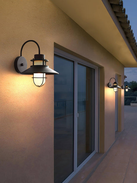 Sconces lit on a stucco wall beside sliding patio doors under a deep eave