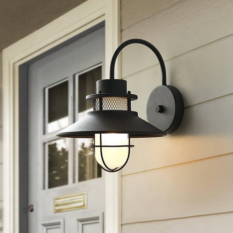 The sconce lit beside a pale gray front door with a brass mail slot
