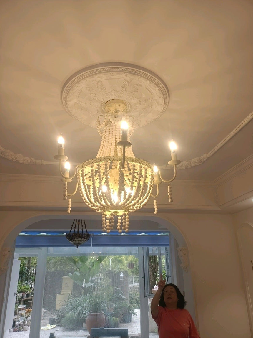 Seen from below against a plaster ceiling rose with a window beyond