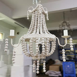 The bead swags and the nine candle arms seen close, the frame photographed in a store room