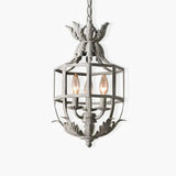 A pale metal cage lantern with a leaf crown on top and three candle lamps inside