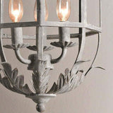 The three candle arms above the curled leaf base inside the cage