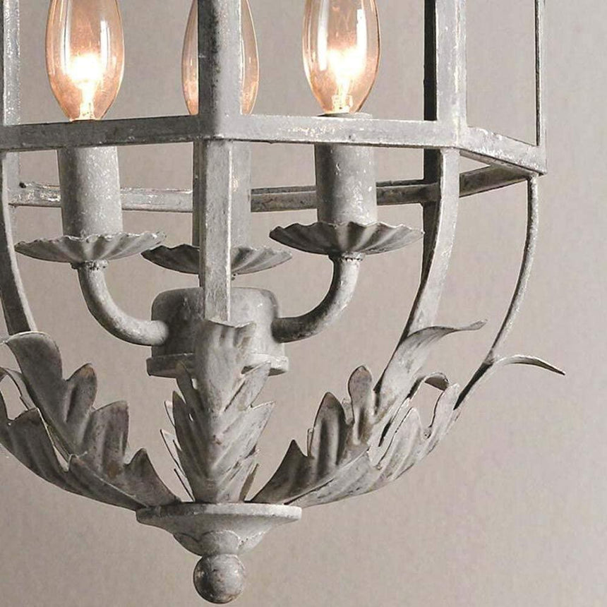 The three candle arms above the curled leaf base inside the cage