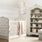 Lit in a nursery above a crib with a tufted headboard and a painted bookcase