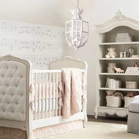 Lit in a nursery above a crib with a tufted headboard and a painted bookcase