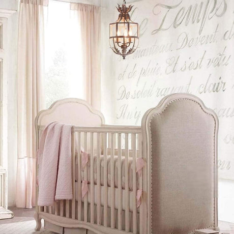 Hung in a pale pink nursery above a crib beside an upholstered headboard