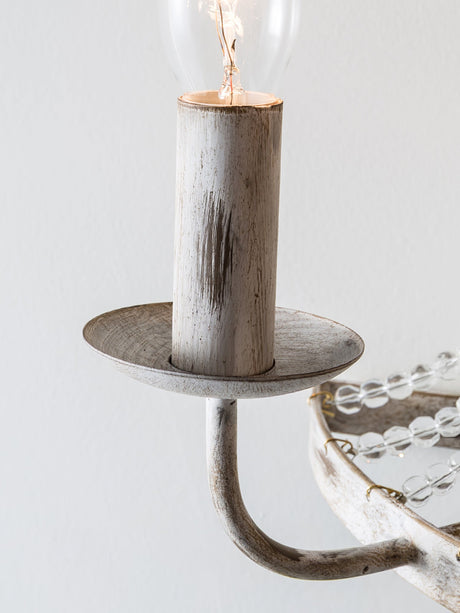 Close view of a distressed white candle cup, its drip plate and the bead strands