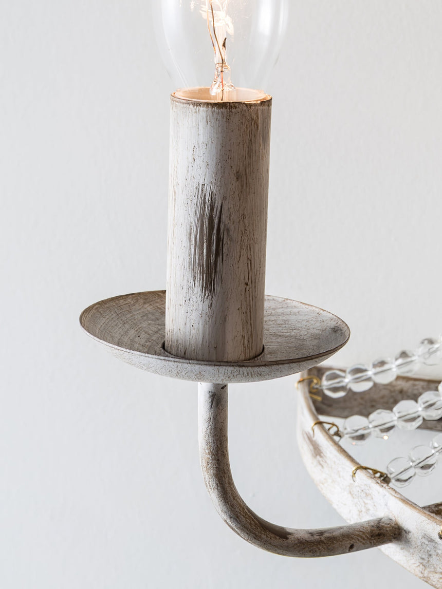Close view of a distressed white candle cup, its drip plate and the bead strands