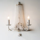 The two arm version lit on a pale wall, the bead strands catching the light