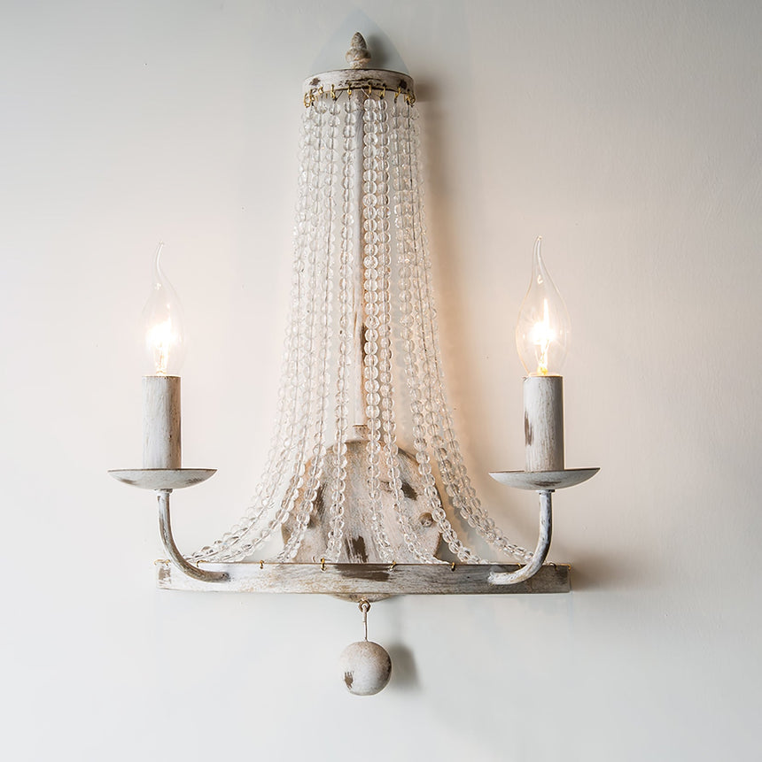 The two arm version lit on a pale wall, the bead strands catching the light