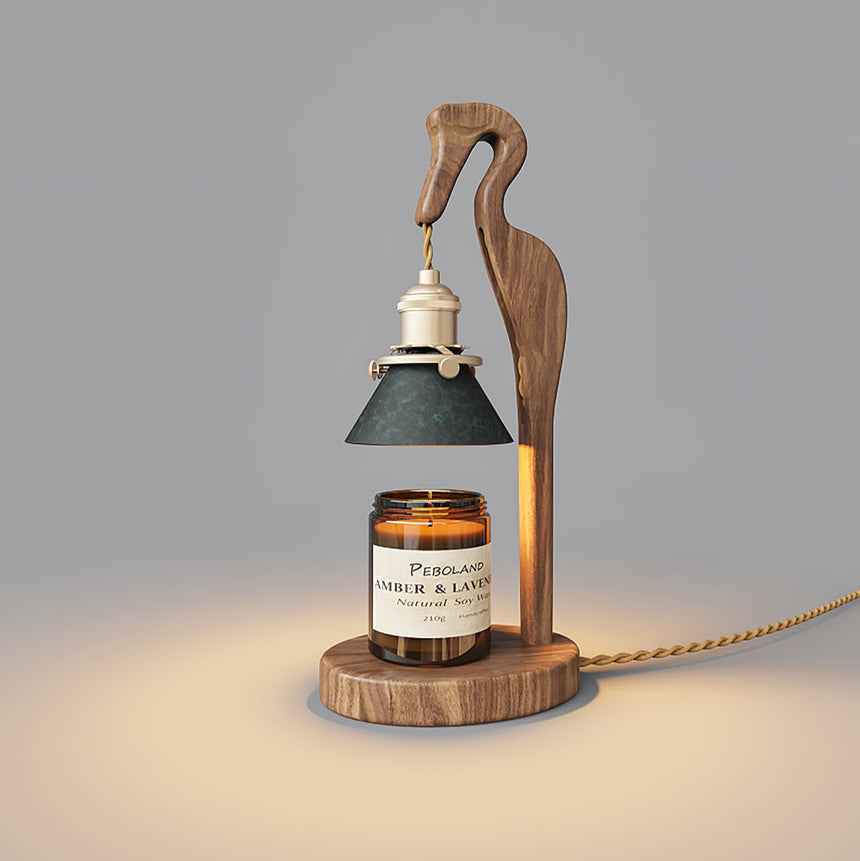 Heron lamp lit above a candle jar against a plain gray ground