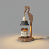 Heron lamp lit above a candle jar, the green shade glowing warm