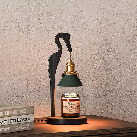 Heron lamp lit on a console beside a book and a paint color box