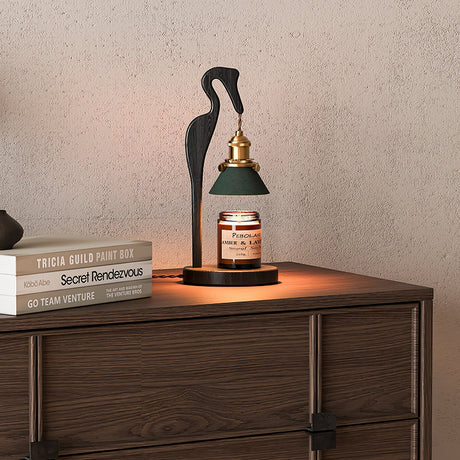 Heron lamp lit on a dark dresser beside two stacked books