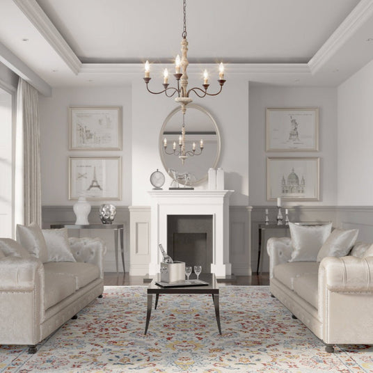 Seen from the doorway of a gray living room with a fireplace, two sofas and a patterned rug
