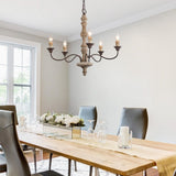 Above a long wood dining table set with glasses, tall window and dark chairs alongside