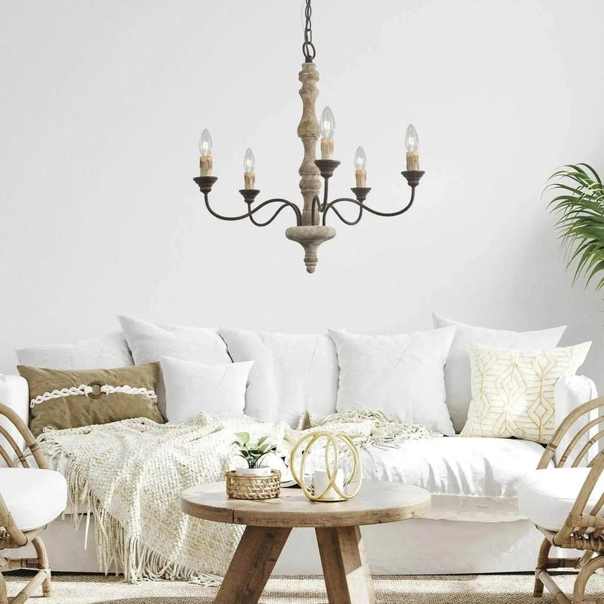 Lit above a white sofa and a small round wood coffee table with cushions and a throw