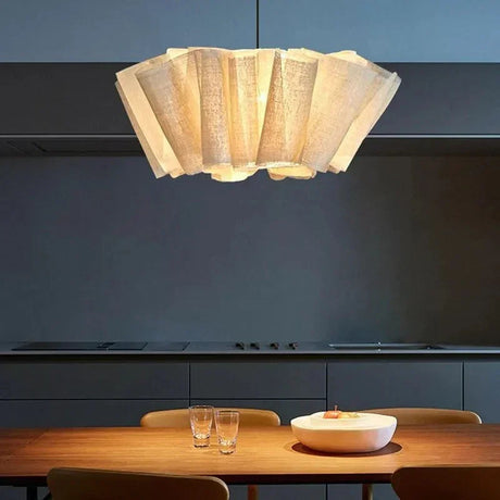 Pleated fabric shade lit above a long counter in a dark room