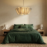 Pleated fabric shade above a bed with dark green bedding